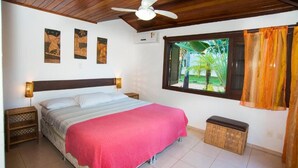 A bedroom with a bed, a ceiling fan, a window with curtains, and wall art. - Vrbo Property (Acu da Torre (Praia do Forte))