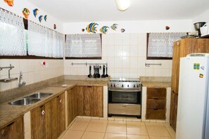 A kitchen with wooden cabinets, a stainless steel stove, and a refrigerator. - Casa Giada - Oceanfront Villa in Praia do Forte - Private Pool and 4 Suites (Acu da Torre (Praia do Forte))