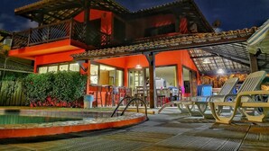A two-story building with a covered patio area, a swimming pool, and lounge chairs. - Vrbo Property (Acu da Torre (Praia do Forte))