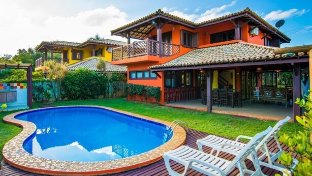 A residential property with a swimming pool, outdoor seating, and a covered patio area. - Vrbo Property (Acu da Torre (Praia do Forte))