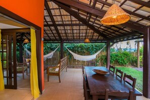 An outdoor dining area with a wooden table and chairs, a hammock, and a view of the sea. - Casa Giada - Oceanfront Villa in Praia do Forte - Private Pool and 4 Suites (Acu da Torre (Praia do Forte))