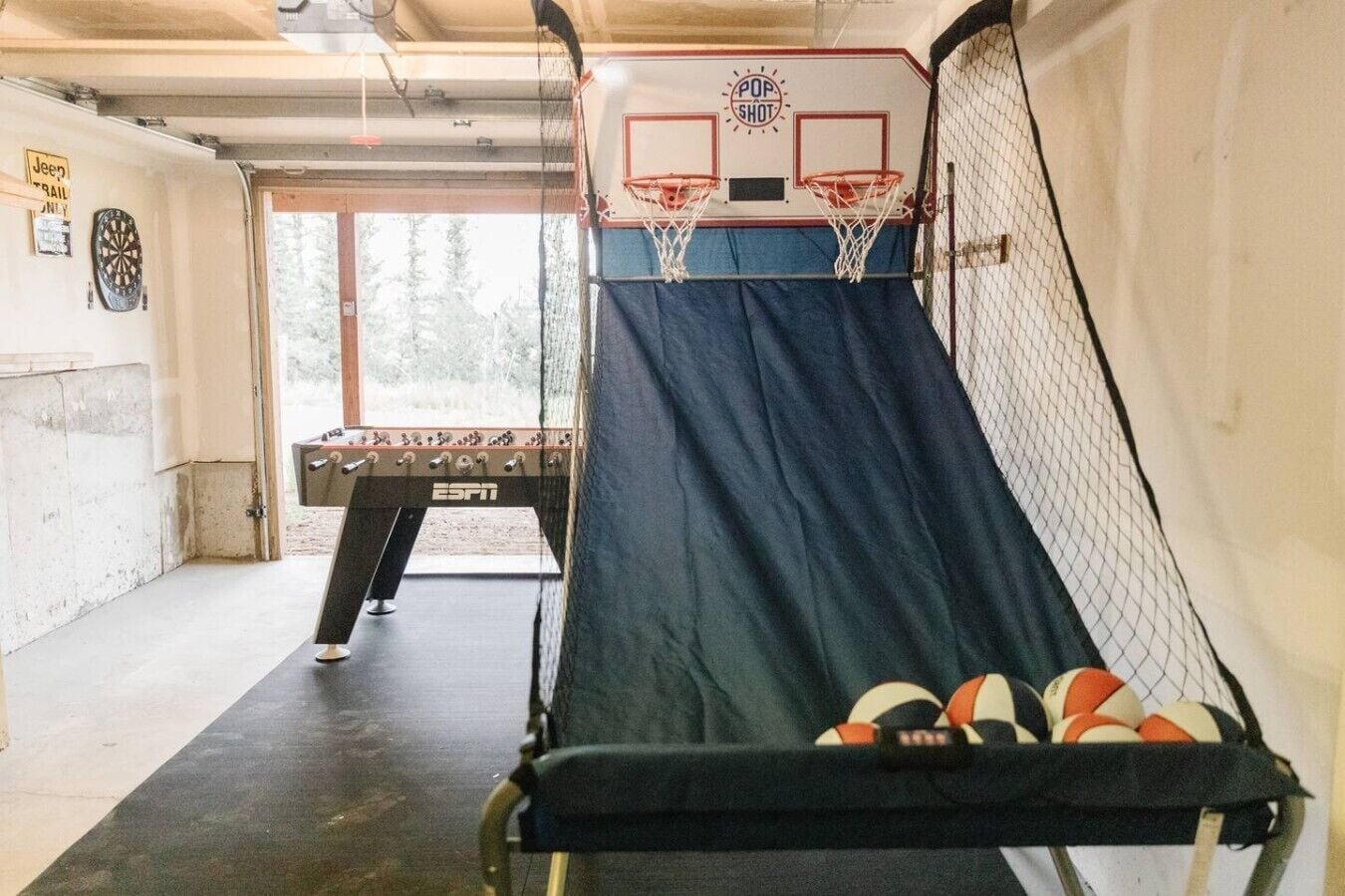 A basketball court with a net, a basketball hoop, and a foosball table.