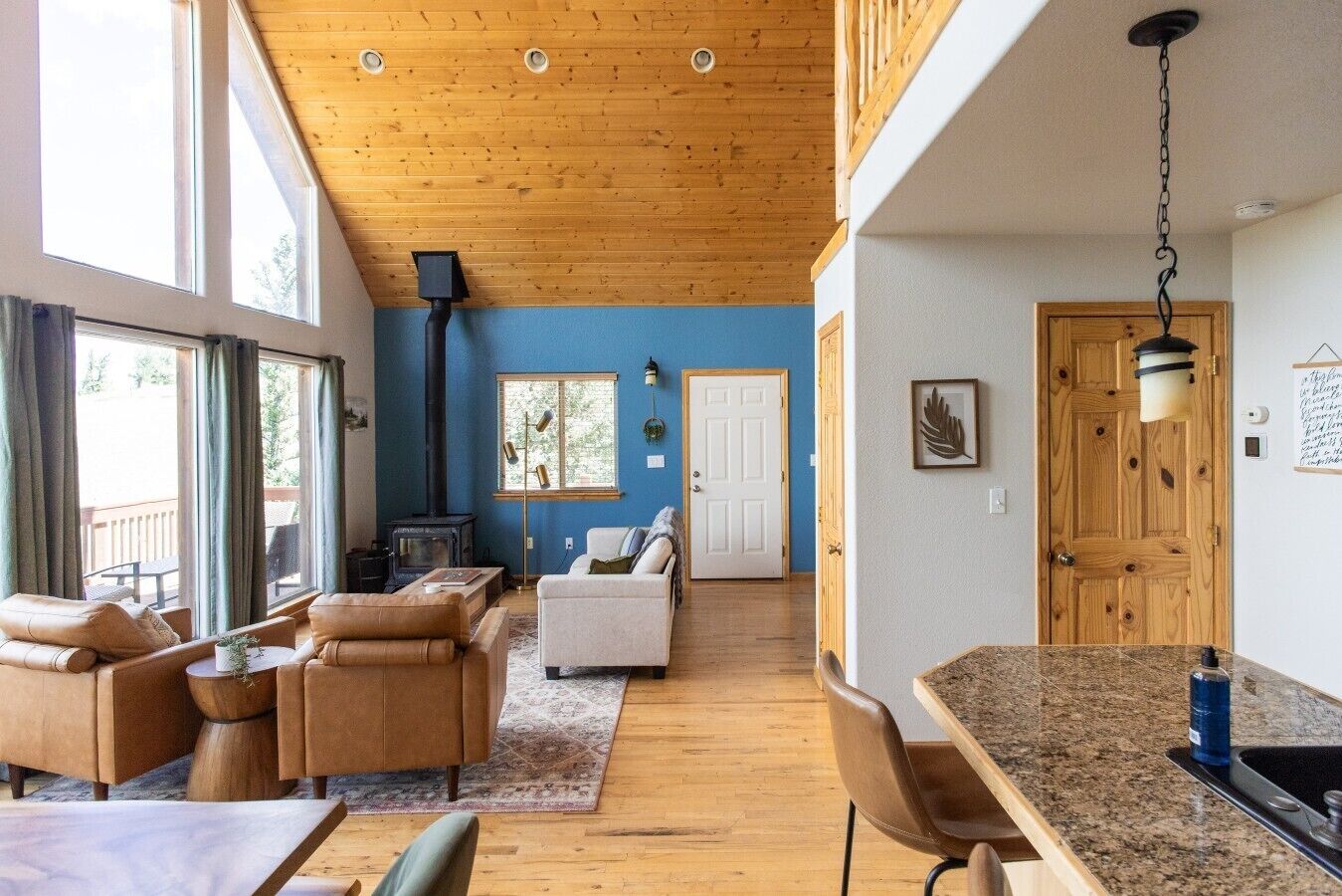 Un salón amplio con techo alto, chimenea y vistas al exterior gracias a amplias ventanas.