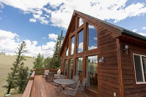 Eine Holzhütte mit einer Terrasse, großen Fenstern und Sitzgelegenheiten im Freien.