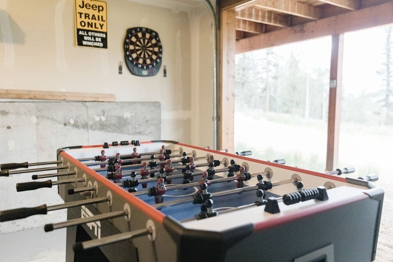 Una mesa de fútbol de mesa en una habitación con un dardo y un letrero que dice 'Jeep Trail Only'.