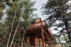 Eine Holzhütte mit Balkon, umgeben von Bäumen.