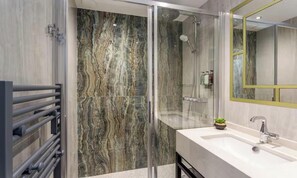 A modern bathroom with a glass shower enclosure, a white sink, and a mirror with a gold frame. - COMBINING THE TIMELESS CHARACTER OF A PARISIAN CONTEMPORARY DESIGN - EIFFEL (Paris)