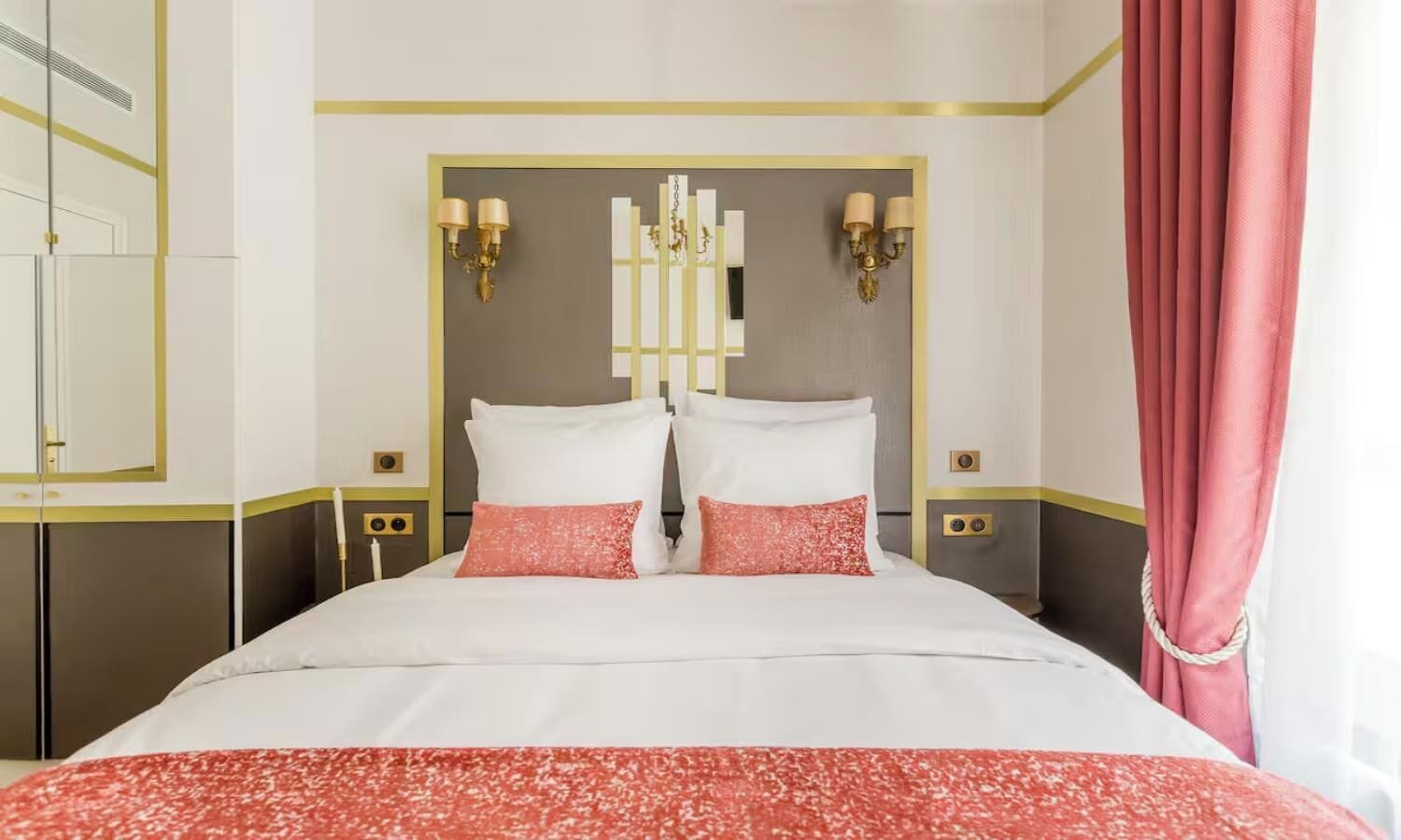 A hotel room with a large bed, two bedside tables, a mirror, and a curtain.
