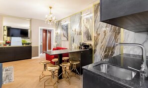 A modern kitchen with a marble backsplash, a black countertop, and gold bar stools. - COMBINING THE TIMELESS CHARACTER OF A PARISIAN CONTEMPORARY DESIGN - EIFFEL (Paris)