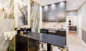 Une cuisine moderne dotée de plans de travail en marbre, d’appareils électroménagers en acier inoxydable et d’un coin bar avec des tabourets.