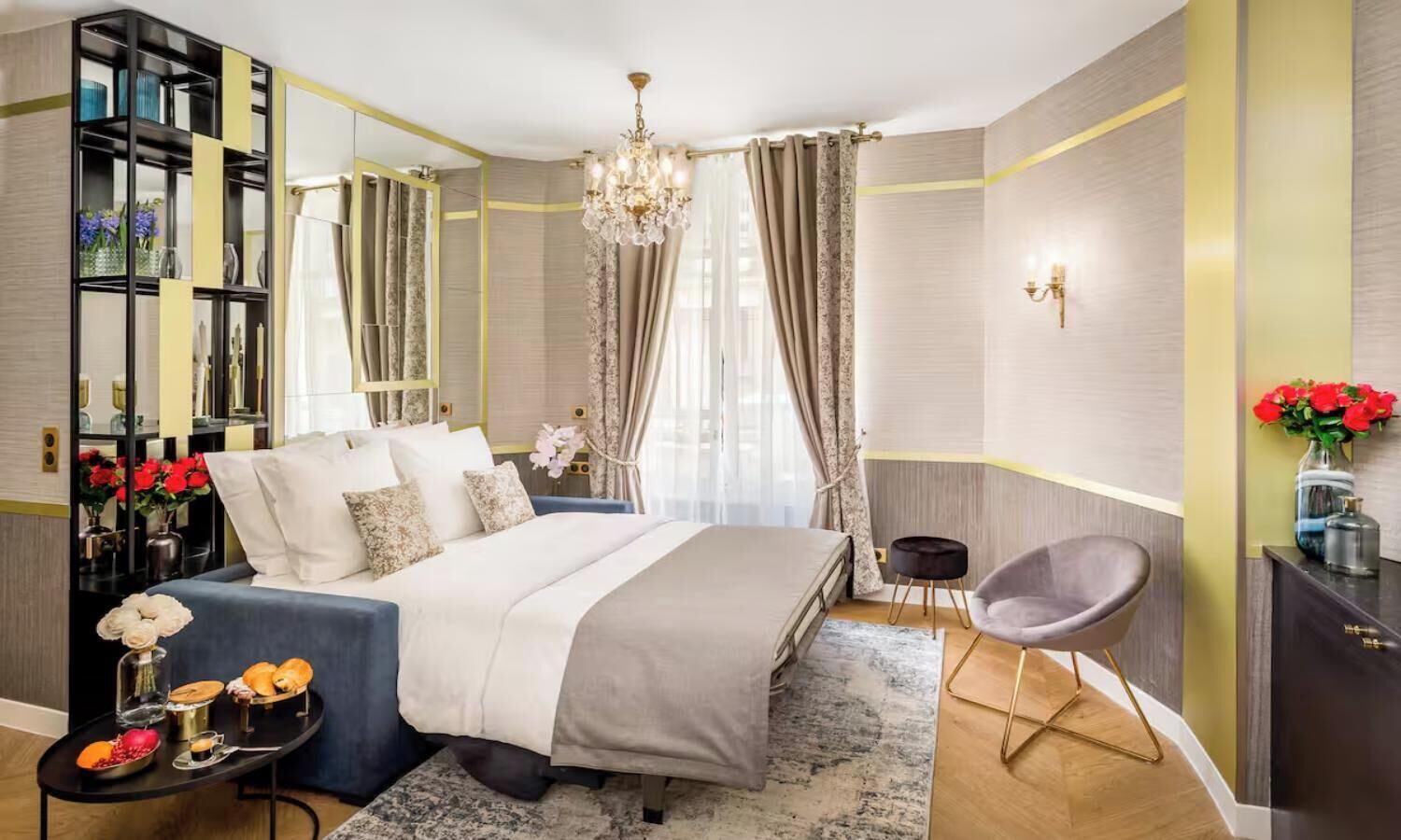 A modern bedroom with a bed, bedside tables, a chair, a mirror, and a chandelier.