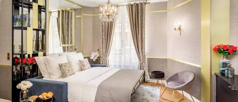 A modern bedroom with a bed, bedside tables, a chair, a mirror, and a chandelier.
