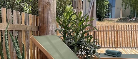 Una terraza de madera con una mesa lista para una comida, rodeada por una valla de madera y plantas en macetas.