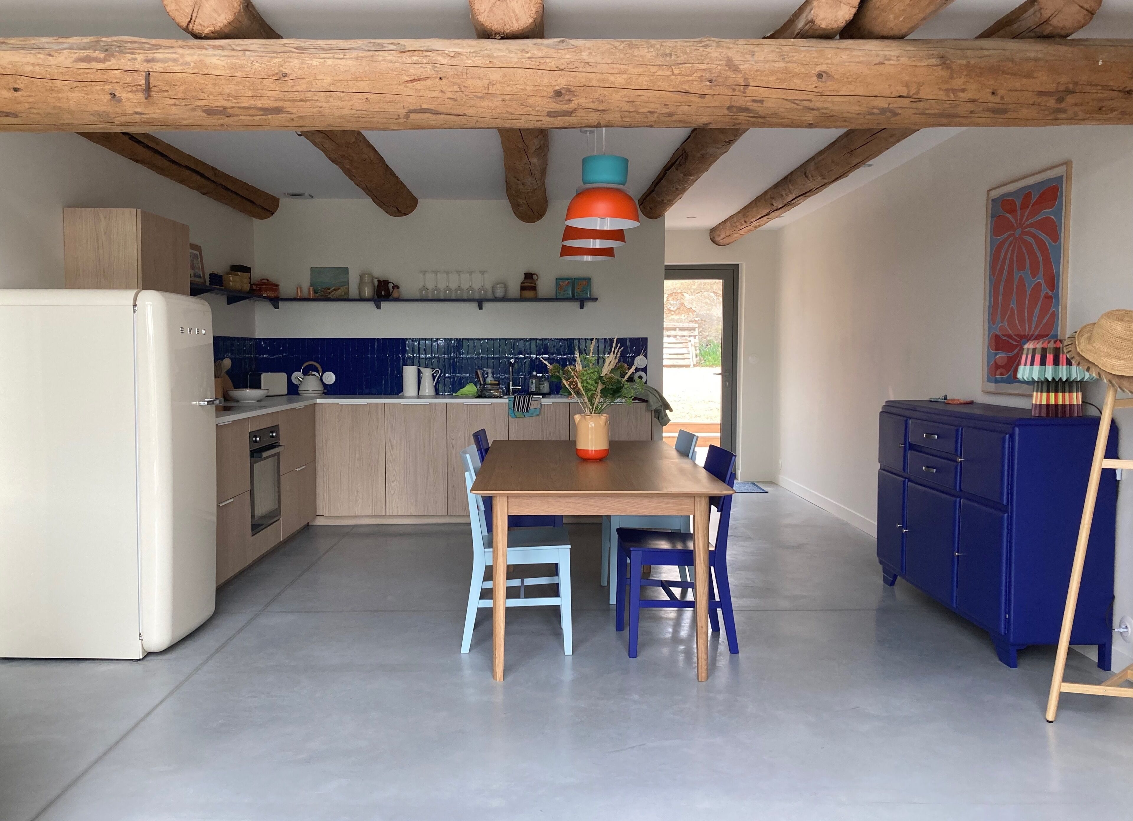 A kitchen with wooden cabinets, a dining table with chairs, and a blue cabinet.