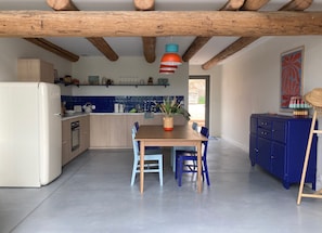 A kitchen with wooden cabinets, a dining table with chairs, and a blue cabinet. - Vacation rental in Haute-Loire with a pool and views of the countryside—perfect for relaxing (Paulhaguet)