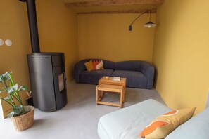 A cozy living room with a sofa, a small wooden table, a black heater, and a potted plant. - Vacation rental in Haute-Loire with a pool and views of the countryside—perfect for relaxing (Paulhaguet)