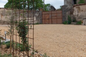 A gravel courtyard with a metal fence and a gate in the background. - Vacation rental in Haute-Loire with a pool and views of the countryside—perfect for relaxing (Paulhaguet)