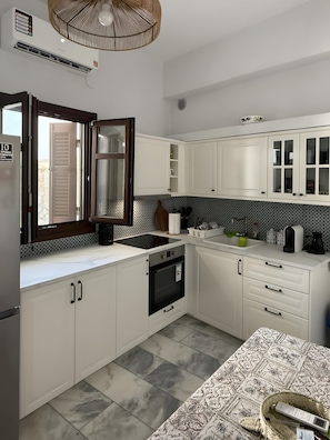 A modern kitchen with white cabinetry, a built-in oven, and a patterned backsplash.