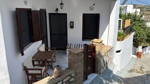 A white building with a balcony, wooden furniture, and a stone bench. - SimpleGreece Skyros Traditional Holiday Home with Balcony, Wi-Fi & Air Conditioning (Σκύρος)