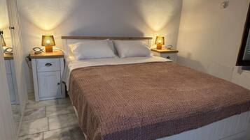A bedroom with a bed, two bedside tables, and a wall-mounted TV.