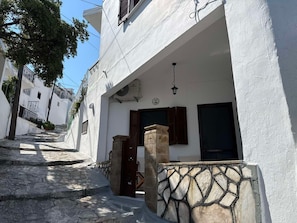 A narrow street with white buildings, a stone staircase, and a stone wall with a geometric pattern.
