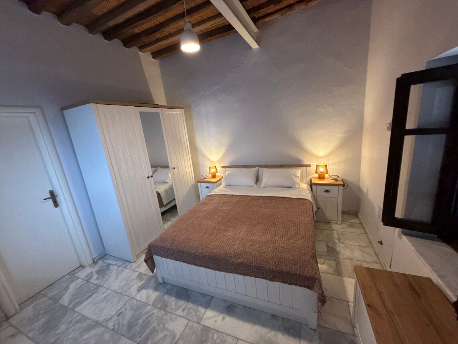 A bedroom with a bed, bedside tables, a wardrobe, and a window.
