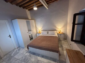 Un dormitorio con cama, mesitas de noche, armario y ventana.