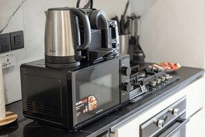A kitchen with a coffee maker, a kettle, and a stove. - Private Jacuzzi / Canal Views / Pool & Gym (Dubai)