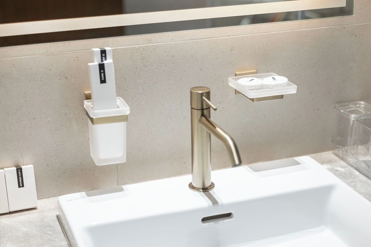 A bathroom sink with a gold faucet, a soap dispenser, and a soap dish.