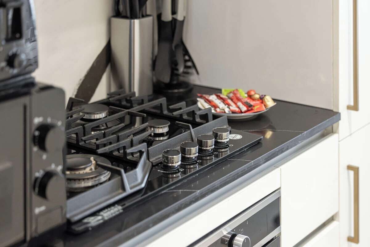 A kitchen with a gas stove, a pot, and a plate of food.