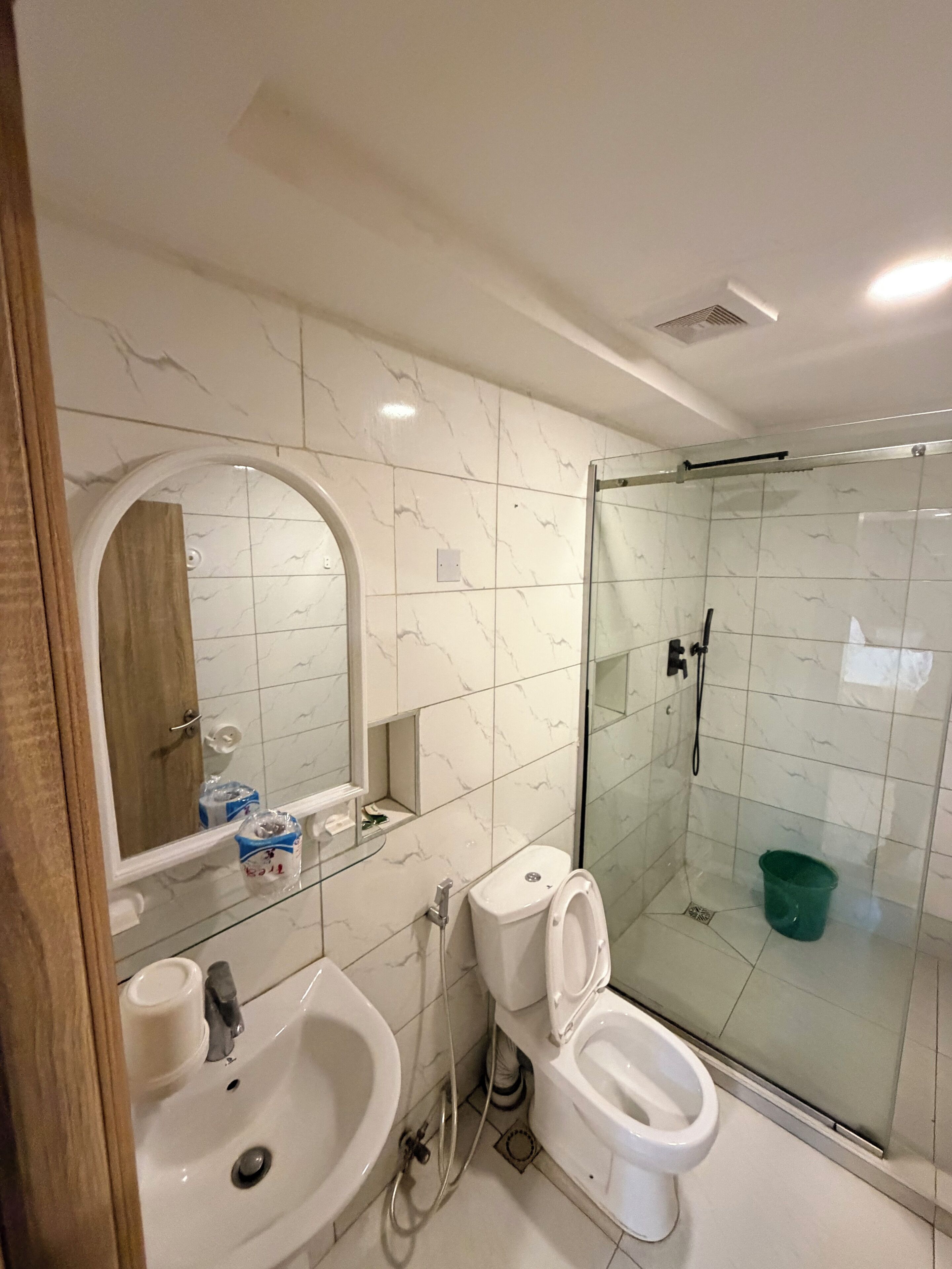 Un baño con ducha envuelta en vidrio, un inodoro y un lavamanos.