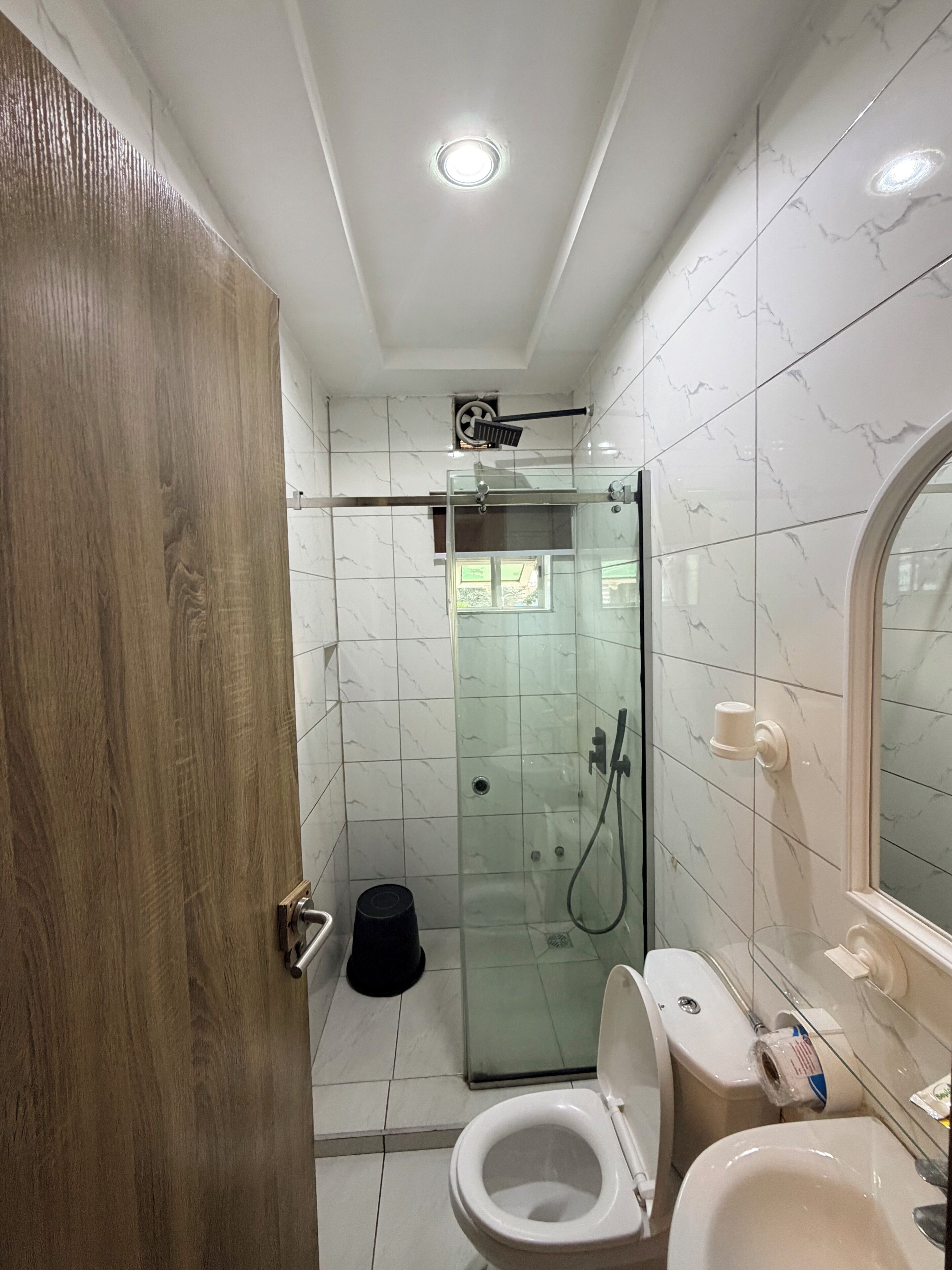 A bathroom with a glass-enclosed shower, a toilet, and a sink.