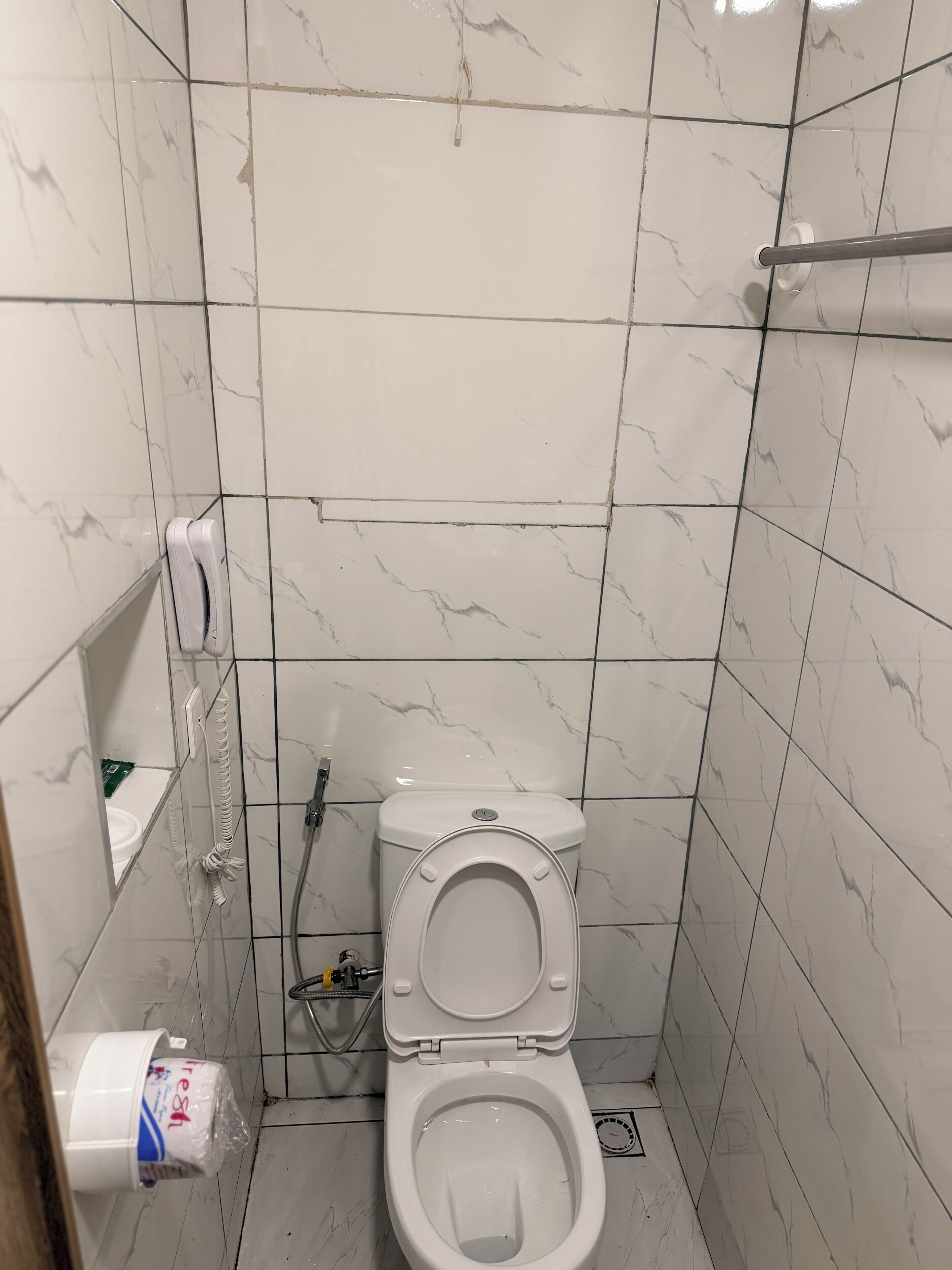 A small, tiled bathroom with a toilet, a hand dryer, and a paper towel dispenser.