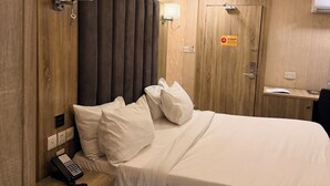 A hotel room with a bed, bedside table, lamp, and a door with a sign. - No 1 by Swiss park (Lagos)
