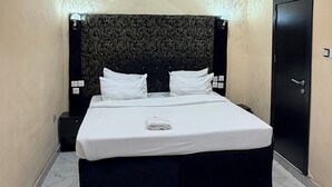 A hotel room with a bed, a headboard, a door, and a nightstand. - No 1 by Swiss park (Lagos)