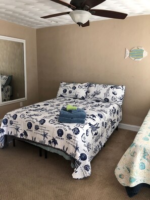 Een slaapkamer met een bed, een plafondventilator, een wandklok en een raam.