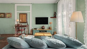 A room with a sofa, a television, a wooden cabinet, and a lamp. - Room 'Suite Jardines' with Mountain View, Shared Pool and Wi-Fi (Breña Alta)