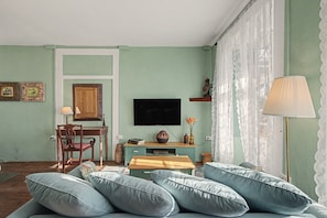 A room with a sofa, a television, a wooden cabinet, and a lamp. - Room 'Suite Jardines' with Mountain View, Shared Pool and Wi-Fi (Breña Alta)