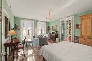 Un dormitorio con cama, escritorio, silla, sofá, cómoda y candelabro.