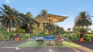 A poolside area with a lounge chair, a small table, and an umbrella. - Room 'Suite Jardines' with Mountain View, Shared Pool and Wi-Fi (Breña Alta)