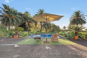 A poolside area with a lounge chair, a small table, and an umbrella. - Room 'Suite Jardines' with Mountain View, Shared Pool and Wi-Fi (Breña Alta)