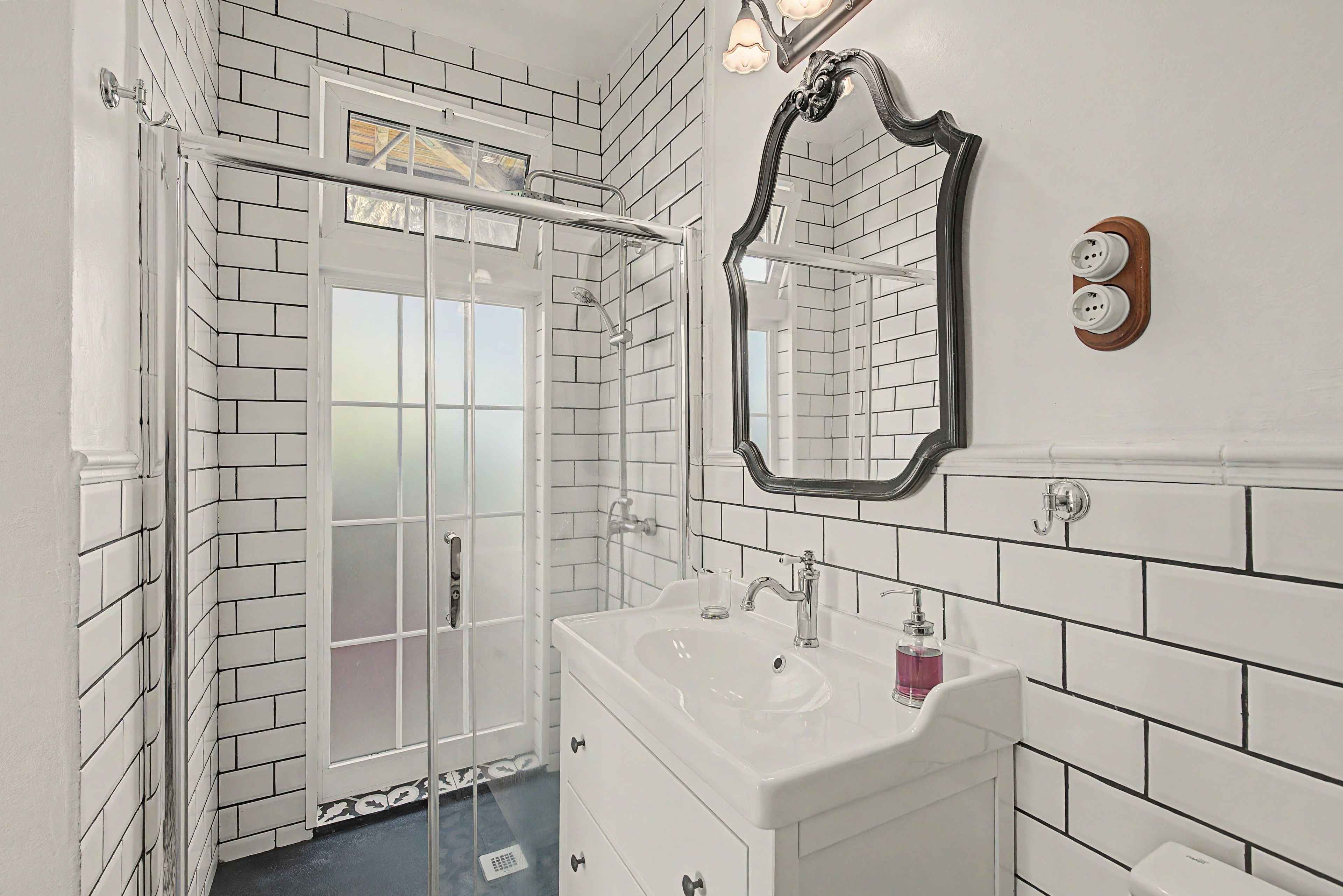 Een badkamer met een douche, wastafel en spiegel.