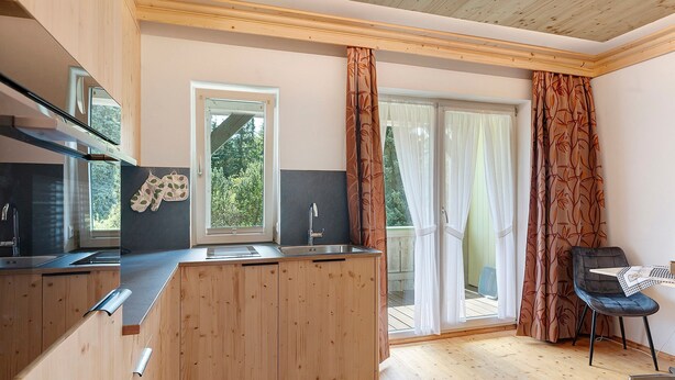 Una cocina moderna con armarios de madera, horno empotrado y ventana con vistas a una terraza.