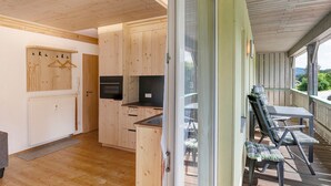 Interior de madera con cocina, comedor y vista a través de un ventanal.