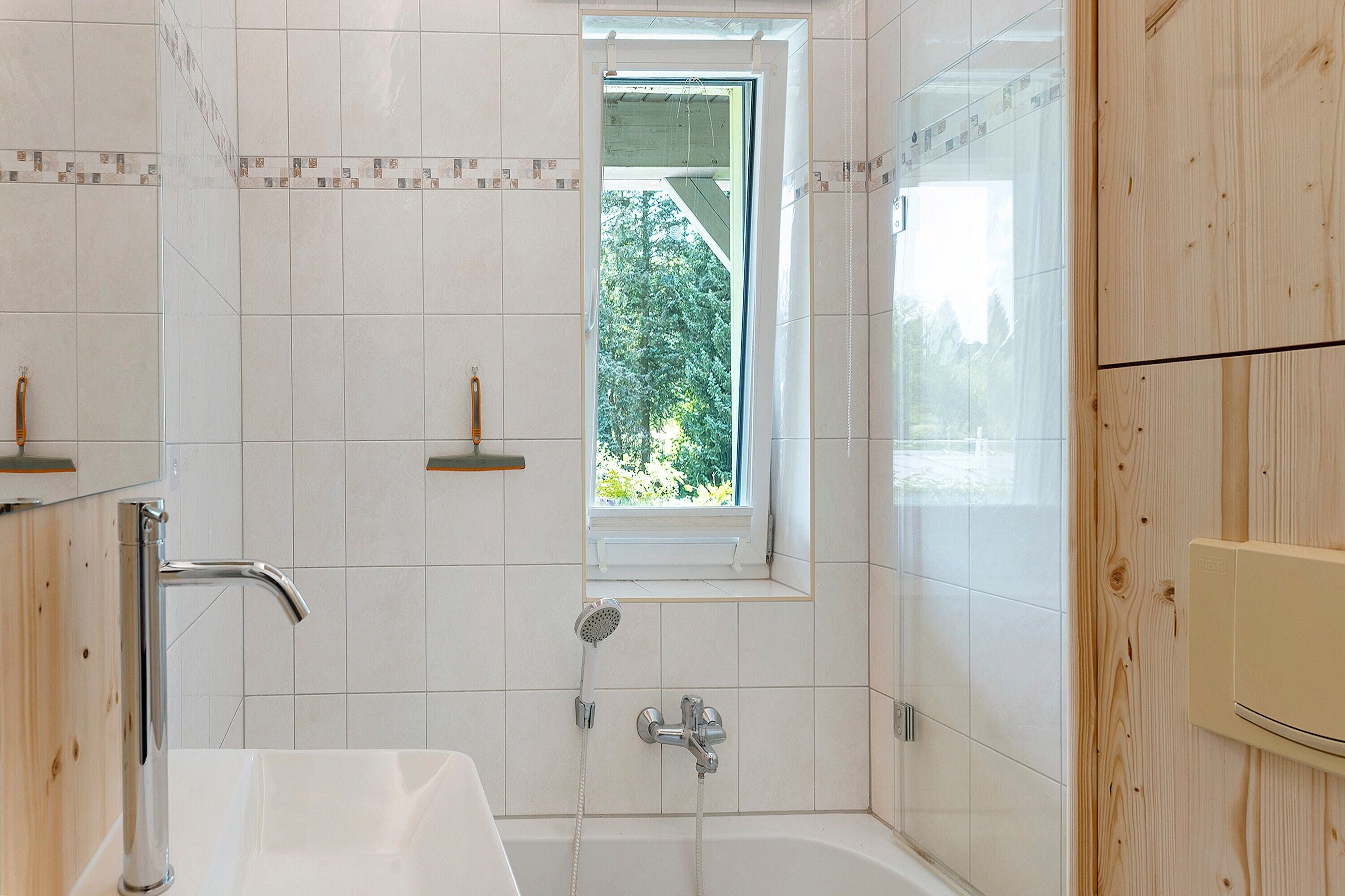 A bathroom with a bathtub, a window, and a shower.