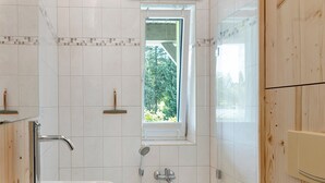 Un baño con bañera, ventana y ducha.