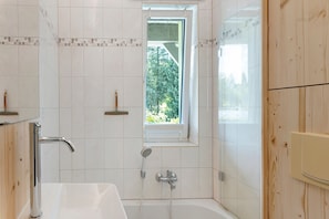 Ein Badezimmer mit einer Badewanne, einem Fenster und einer Dusche.