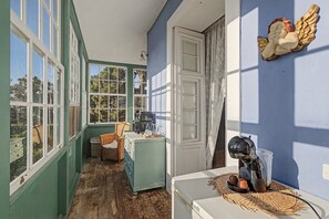 A room with a wooden floor, a window, a door, a wicker chair, a white dresser, and a wall-mounted decorative item. - Suite Balcony Room with Mountain Views, Shared Pool & Wi-Fi (Breña Alta)