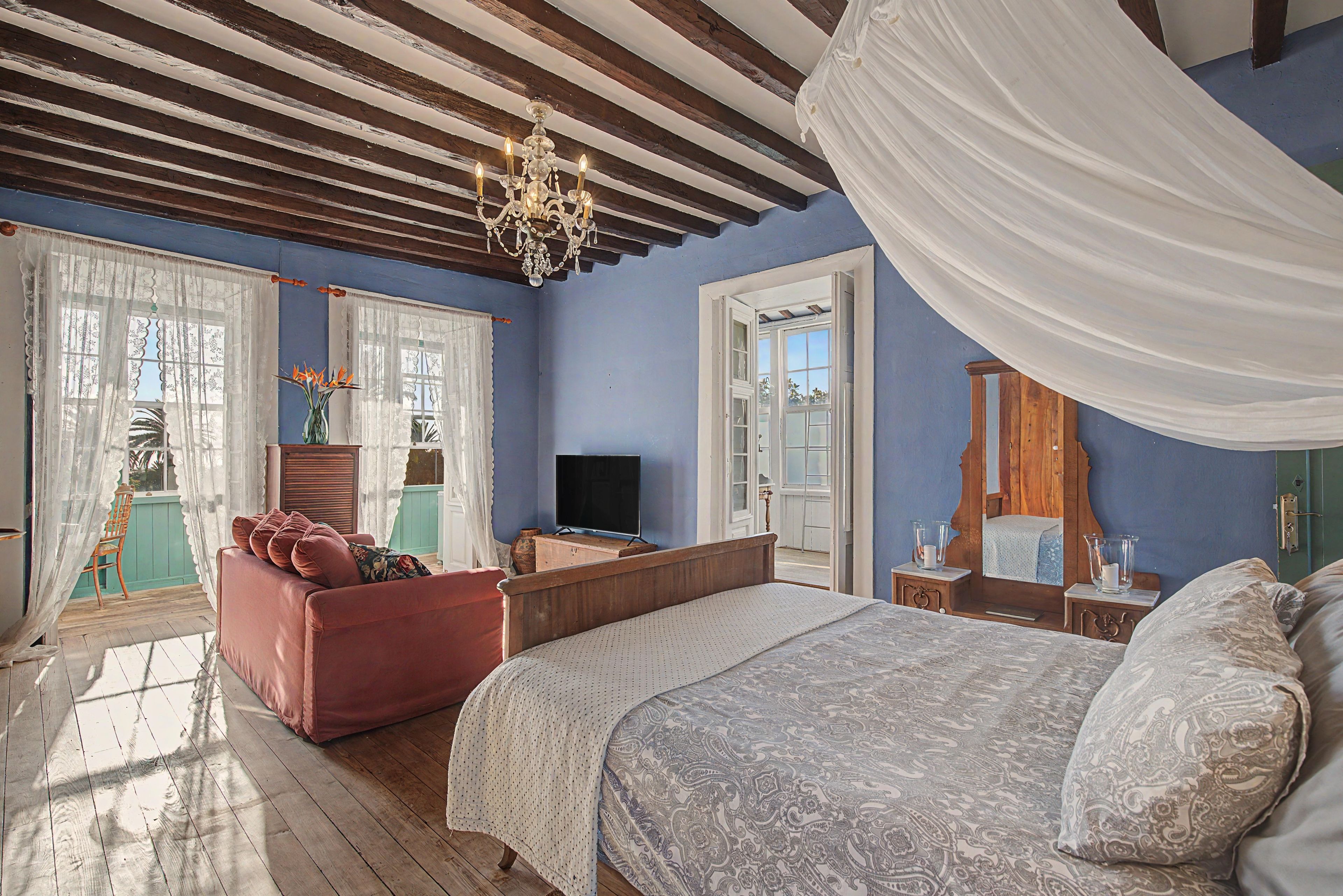 Quarto com cama grande, televisão, cômoda de madeira e cadeira.