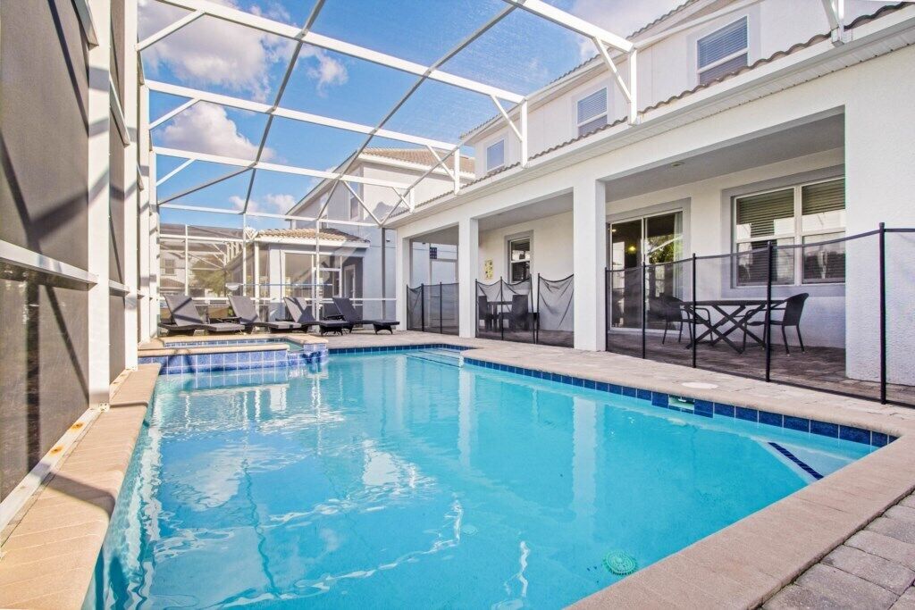 A swimming pool with lounge chairs and a covered patio area.